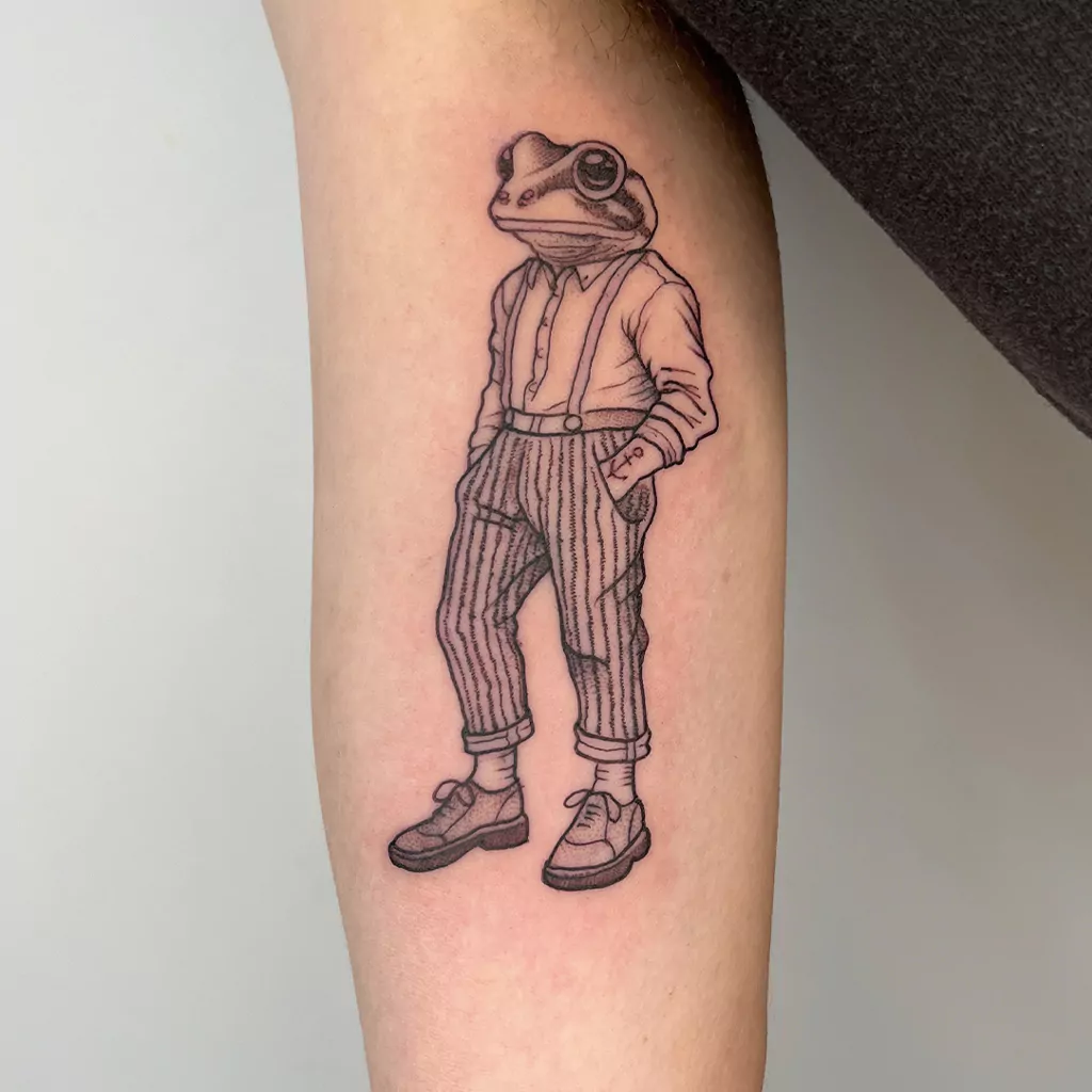 Fineline Tattoo eines Frosches im stylischen Outfit